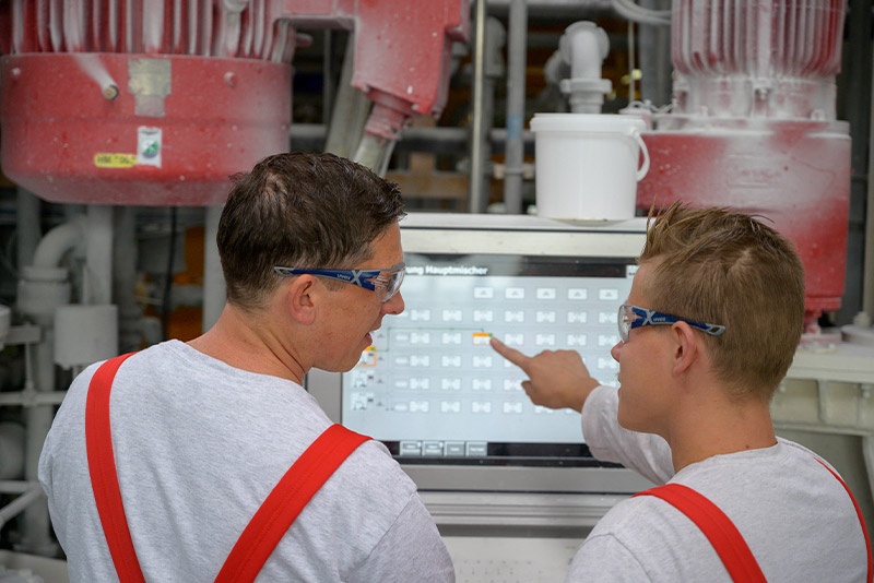 2 Männer schauen gemeinsam auf einen Bildschirm in der Produktion